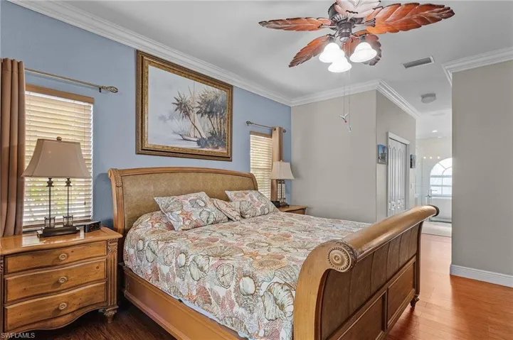 Bedroom with hardwood / wood-style floors, a closet, ceiling fan, and crown molding