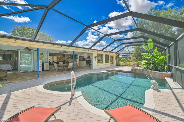 The property features an outdoor swimming pool within a screened enclosure, surrounded by a paved patio area