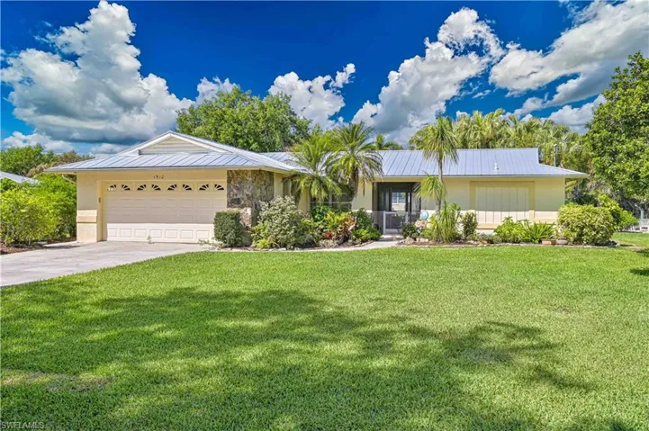 The property features a well-maintained lawn, a paved driveway, and a two-car garage