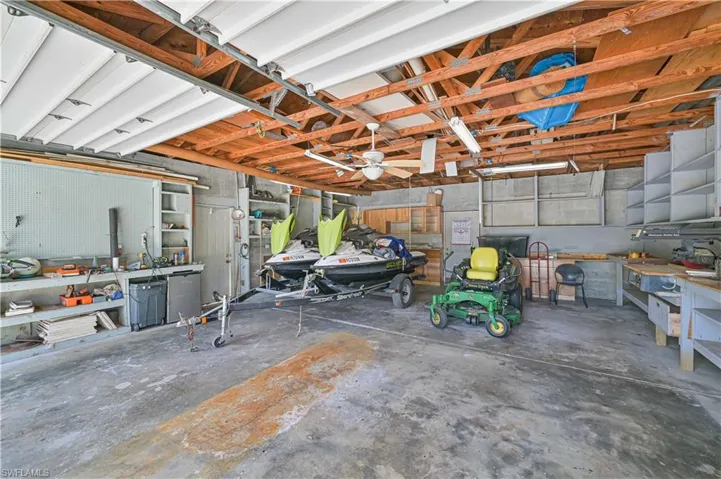 The property features a spacious garage with a concrete floor, exposed wooden ceiling beams, and a ceiling fan