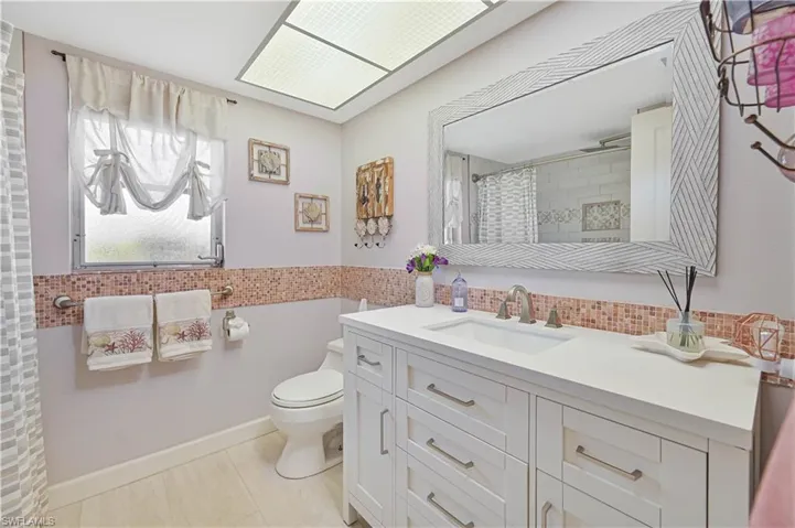 This bathroom features a contemporary vanity with a white countertop and brushed nickel fixtures