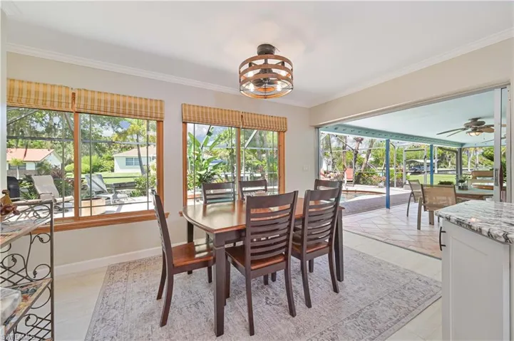 Dining area featuring large windows with natural light, a wood dining table, and direct access to an outdoor screened patio with tiled flooring