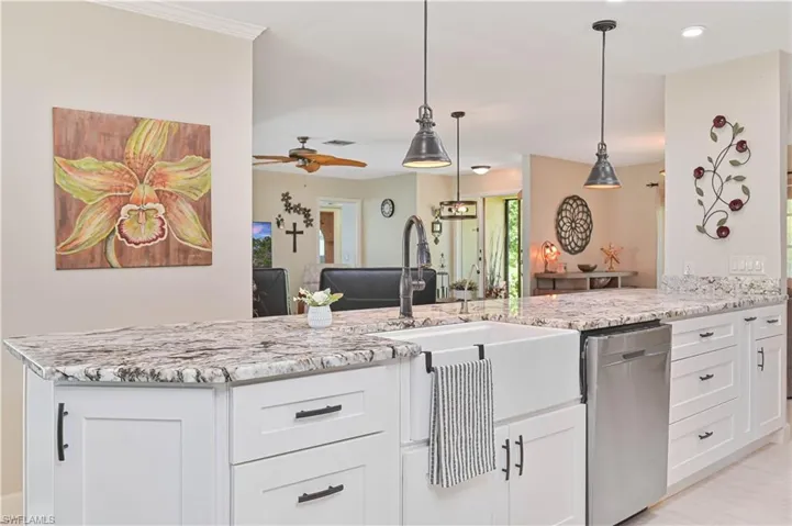 The kitchen features white cabinetry with dark hardware, granite countertops, a farmhouse-style sink, and a stainless steel dishwasher