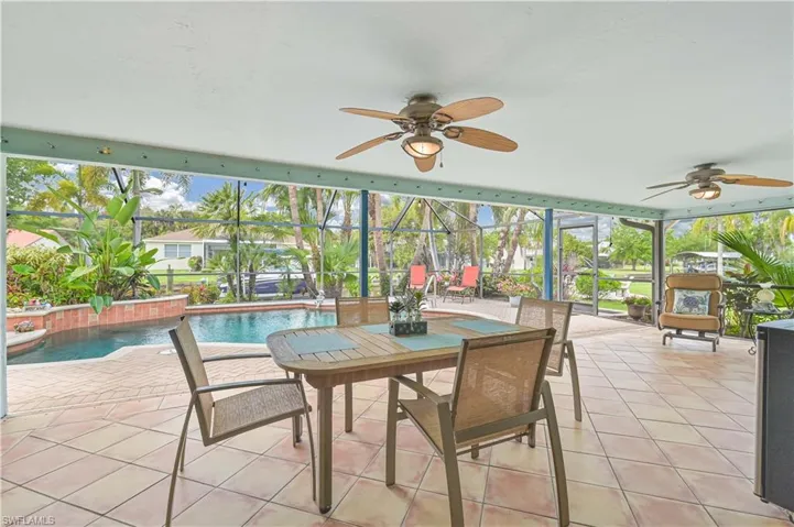 Expansive screened patio featuring two ceiling fans, a dining table with chairs, and tiled flooring