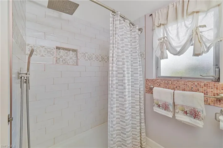 The bathroom features a tiled shower with a niche for toiletries and a rainfall showerhead