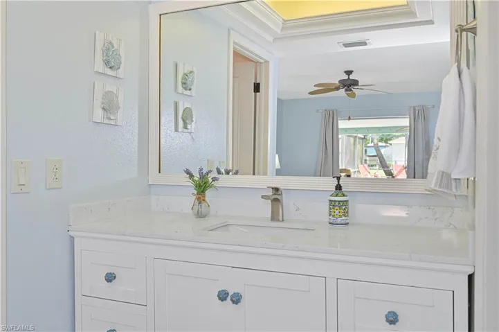 Bright bathroom featuring a white vanity with an integrated sink, a large mirror, and light blue walls