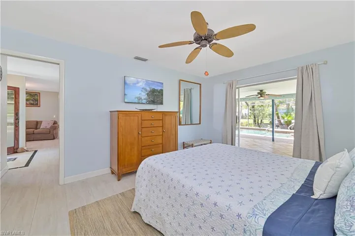 Bright room featuring light-colored walls and flooring, a ceiling fan, and sliding glass doors that open to an outdoor area with a pool