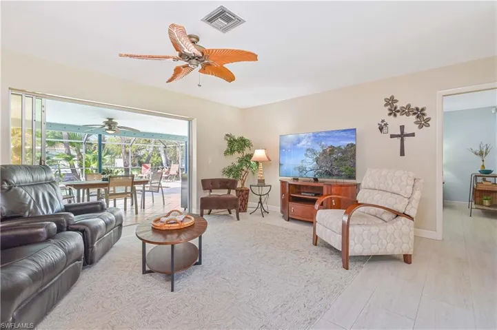 Living area featuring light-colored flooring, a ceiling fan, and a view of an outdoor patio area with a dining table