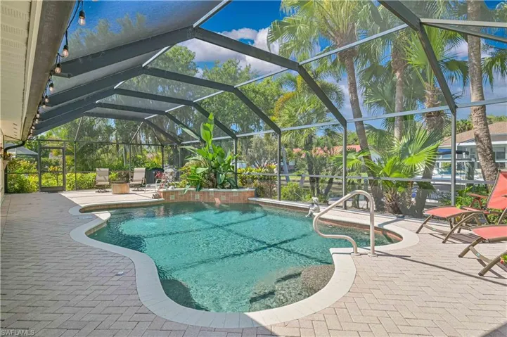 This property features a screened-in swimming pool area with a unique, curvilinear pool design