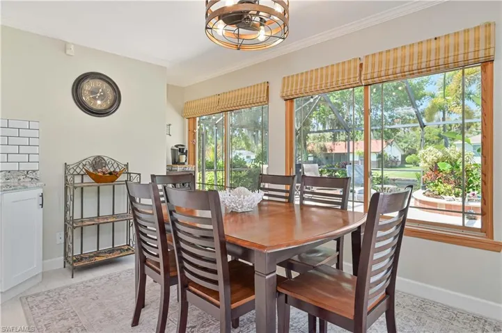 This dining area features a wooden table and chairs, large windows with natural wood frames, and a decorative ceiling light fixture