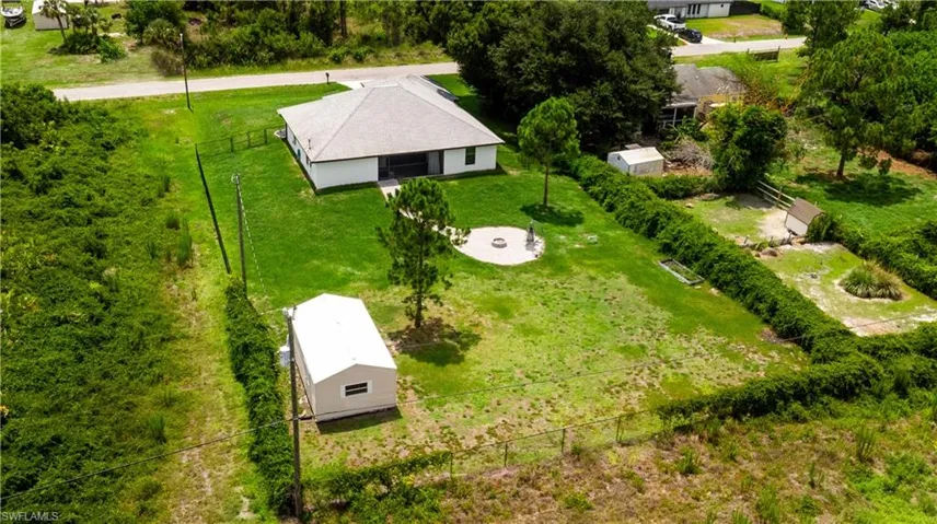 Expansive rear yard featuring a large detached shed, fenced perimeter, and a central fire pit area