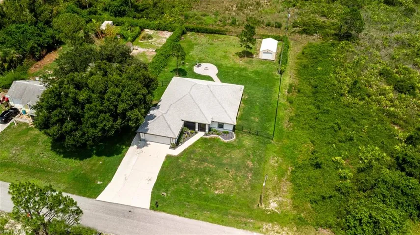 Single-story residence featuring a paved driveway, attached garage, and a fire pit area in the rear yard