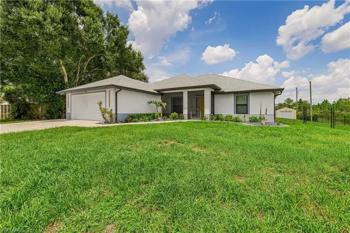 Modern single-story residence featuring a two-car garage, covered entry, and a large front lawn