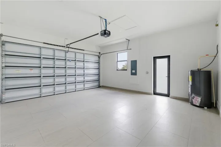 Garage with water heater, electric panel, and a garage door opener