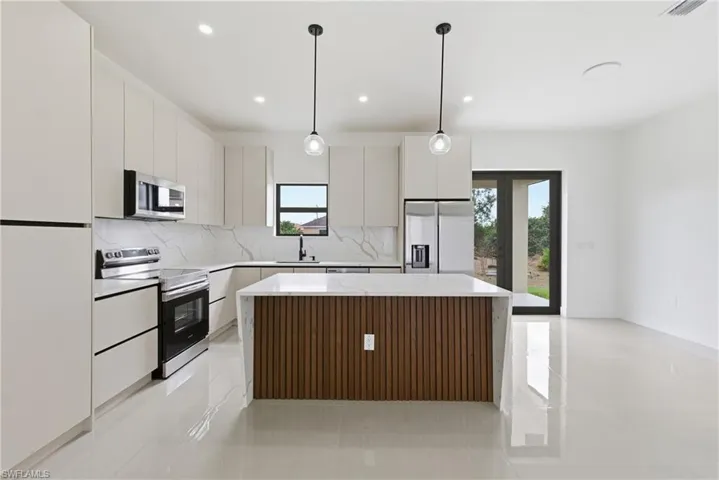 Kitchen with a kitchen island, stainless steel appliances, hanging light fixtures, and light tile patterned floors