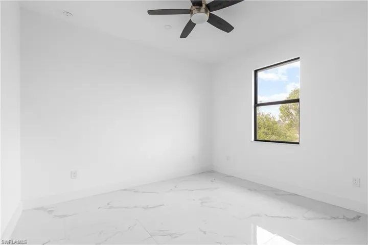 Unfurnished room featuring light marble finish floors and ceiling fan