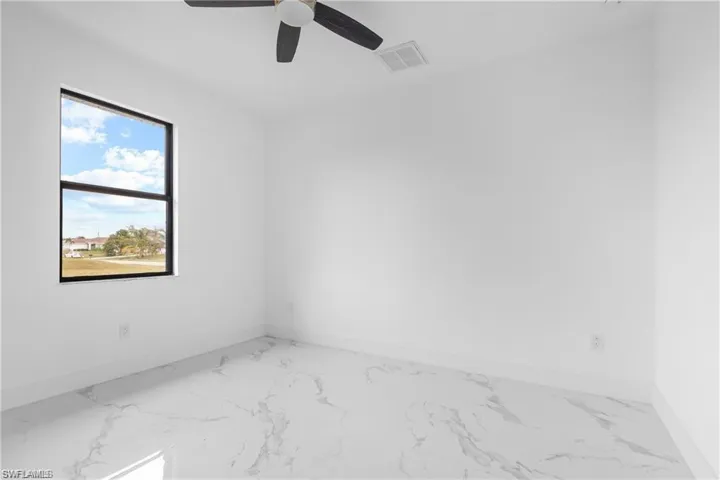 Spare room featuring marble finish floors and ceiling fan