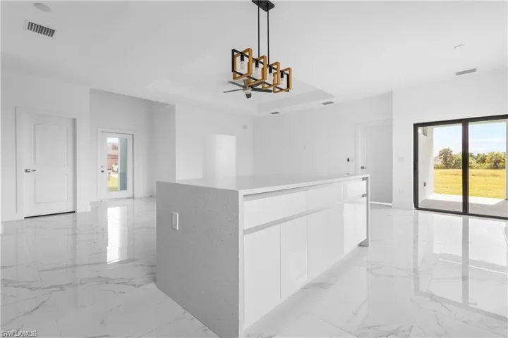 Hallway featuring light marble finish floors, a chandelier, and a tray ceiling