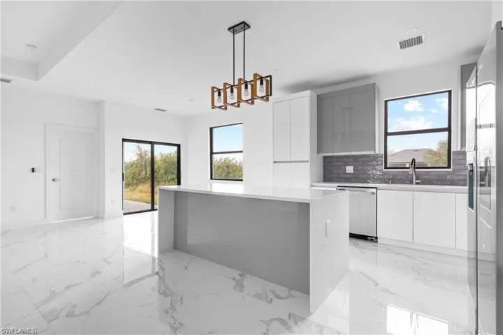 Kitchen featuring modern cabinets, light marble finish flooring, and plenty of natural light