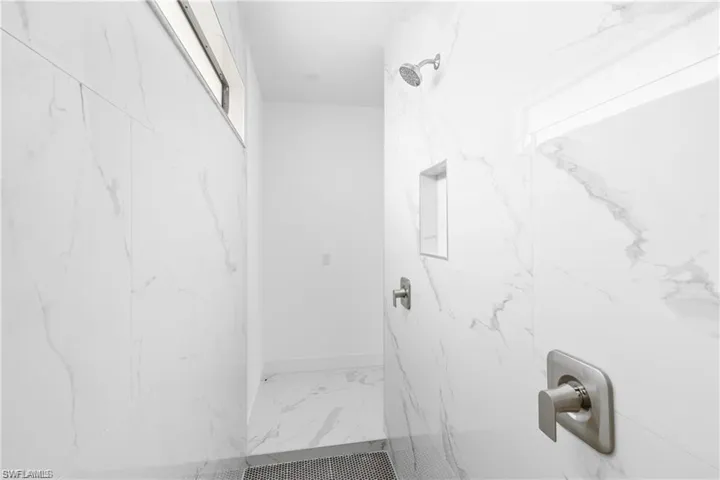 Full bath with a marble finish shower