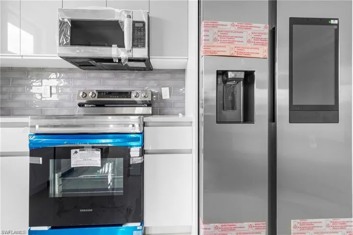 Kitchen with appliances with stainless steel finishes, decorative backsplash, and white cabinets