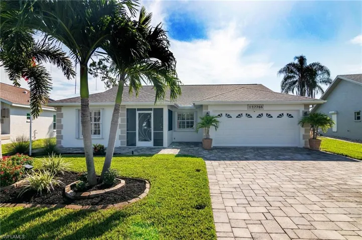 Single story home with stucco siding, an attached garage, a front yard, and decorative driveway
