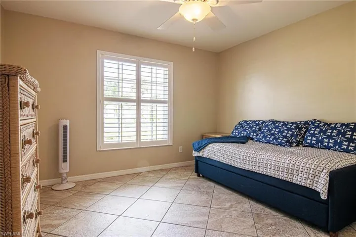 Bedroom with light tile patterned floors and a ceiling fan