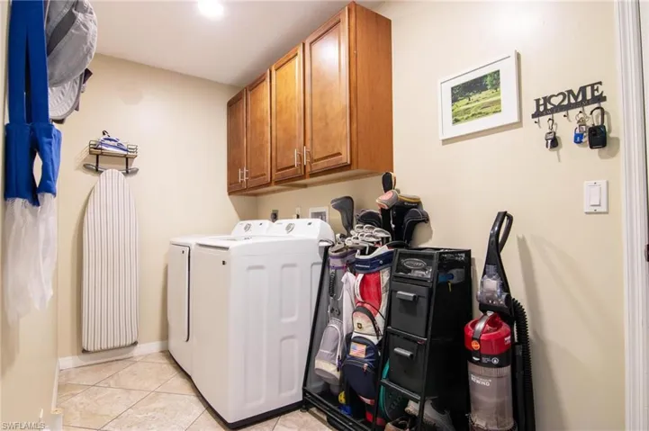 Washroom featuring washing machine and clothes dryer, cabinet space, and light tile patterned floors