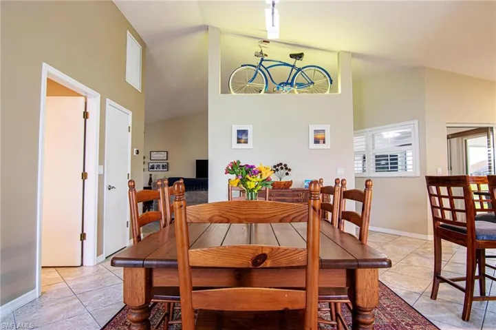 Dining area with a chandelier, high vaulted ceiling, and light tile patterned flooring