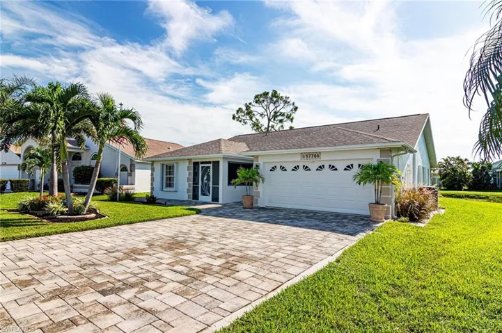 Ranch-style home with decorative driveway, a garage, stucco siding, and a front yard