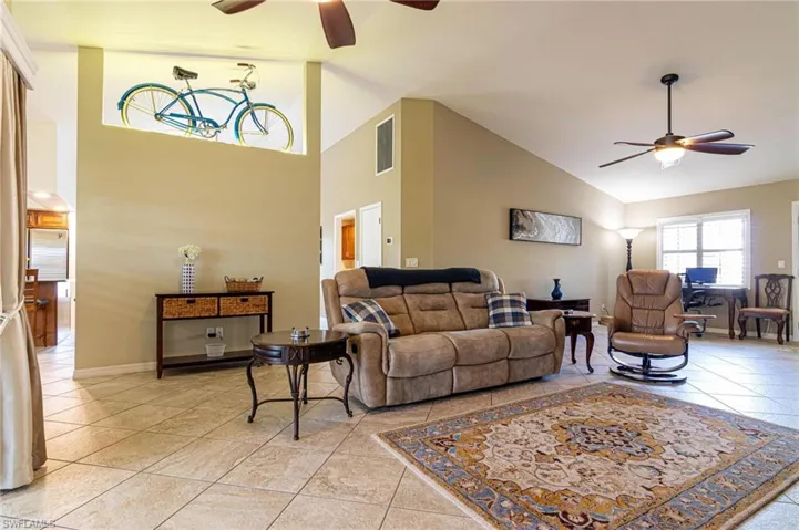 Living area featuring ceiling fan, light tile patterned flooring, and high vaulted ceiling