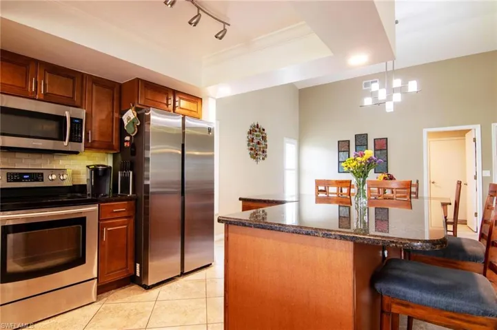 Kitchen with appliances with stainless steel finishes, a breakfast bar, tasteful backsplash, light tile patterned floors, and pendant lighting