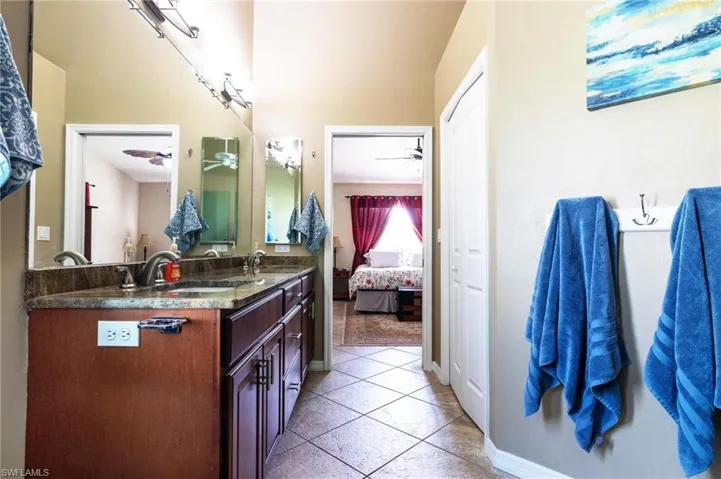 Ensuite bathroom featuring a ceiling fan, double vanity, and tile patterned flooring