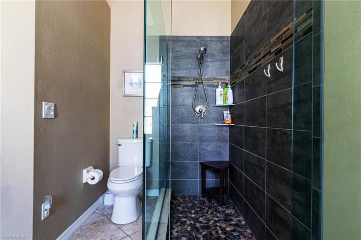 Bathroom with tiled shower and tile patterned floors