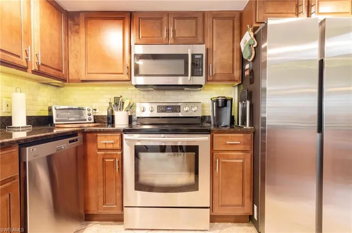 Kitchen featuring appliances with stainless steel finishes, tasteful backsplash, and brown cabinets