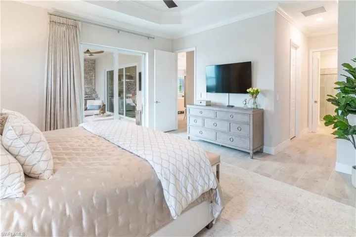 Tiled bedroom with crown molding, ceiling fan, and a tray ceiling