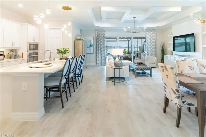 Kitchen with decorative light fixtures, white cabinetry, a breakfast bar area, ornamental molding, and stainless steel appliances