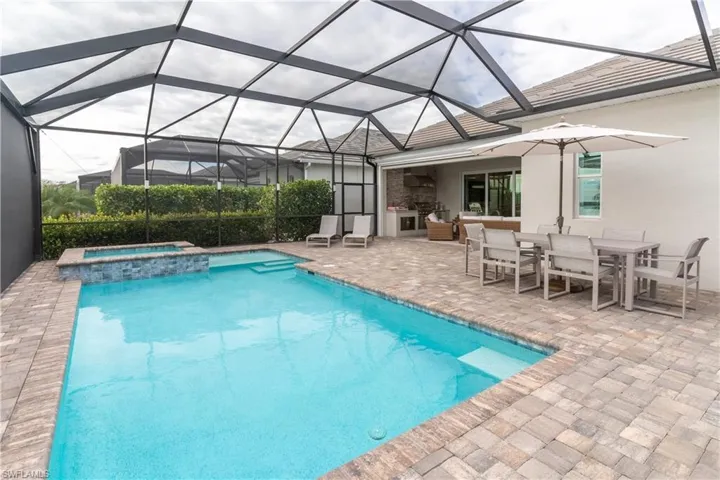 View of swimming pool featuring an in ground hot tub, a patio, and glass enclosure