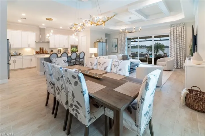 Dining room with crown molding, coffered ceiling, and an inviting chandelier