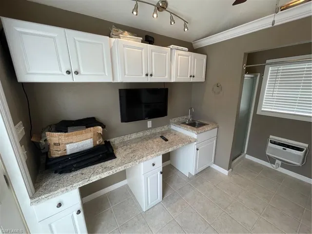 Kitchen with built in desk, white cabinetry, and rail lighting