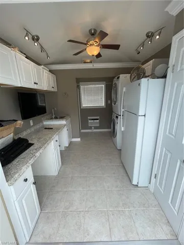Kitchen with white cabinetry, refrigerator, ceiling fan, and light tile floors