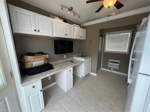 Kitchen with white cabinetry, ornamental molding, built in desk, track lighting, and ceiling fan