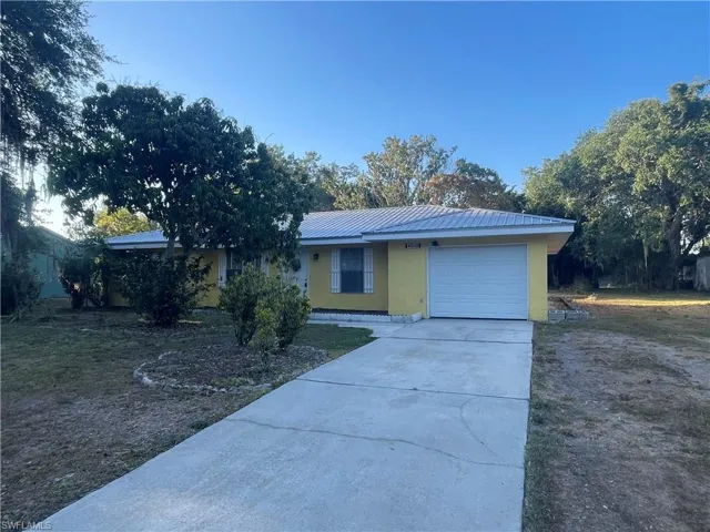 Ranch-style home featuring a garage, stucco siding, driveway, and metal roof