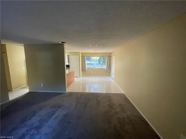 Hallway with light carpet, baseboards, visible vents, a notable chandelier, and a textured ceiling