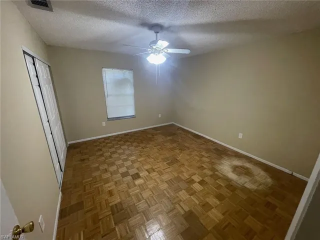 Unfurnished bedroom featuring a textured ceiling, visible vents, ceiling fan, and baseboards