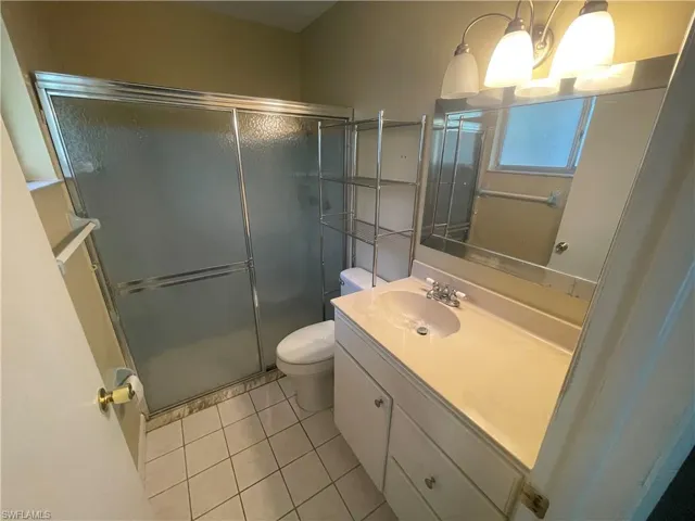 Full bathroom with a stall shower, vanity, toilet, and tile patterned flooring