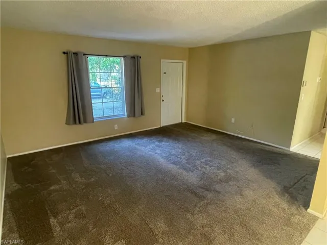 Carpeted empty room with baseboards and a textured ceiling