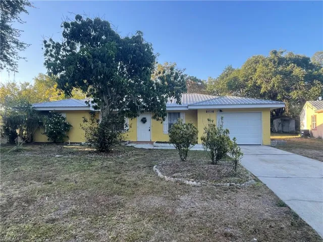 Single story home featuring a garage, stucco siding, driveway, and metal roof