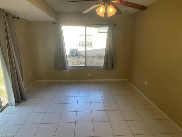 Unfurnished room featuring light tile patterned flooring, a ceiling fan, and baseboards