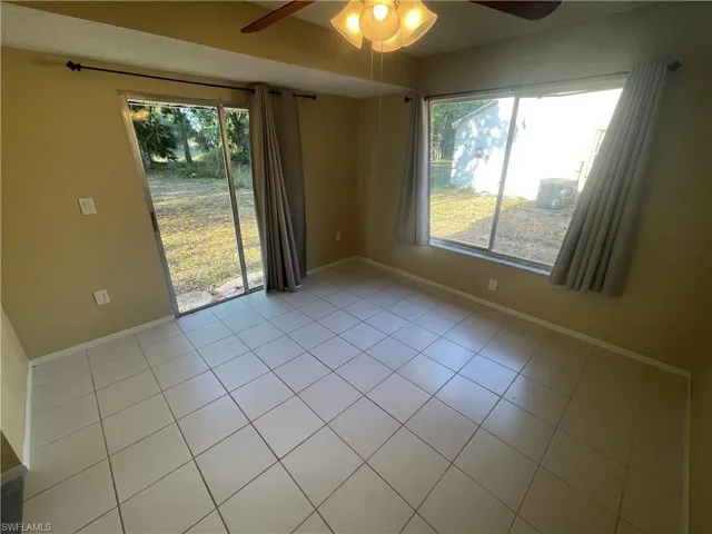 Spare room with baseboards, light tile patterned floors, and a ceiling fan
